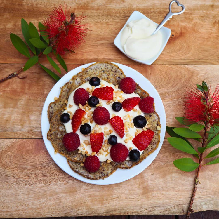 Low carb keto pancakes topped with nuts cream and berries